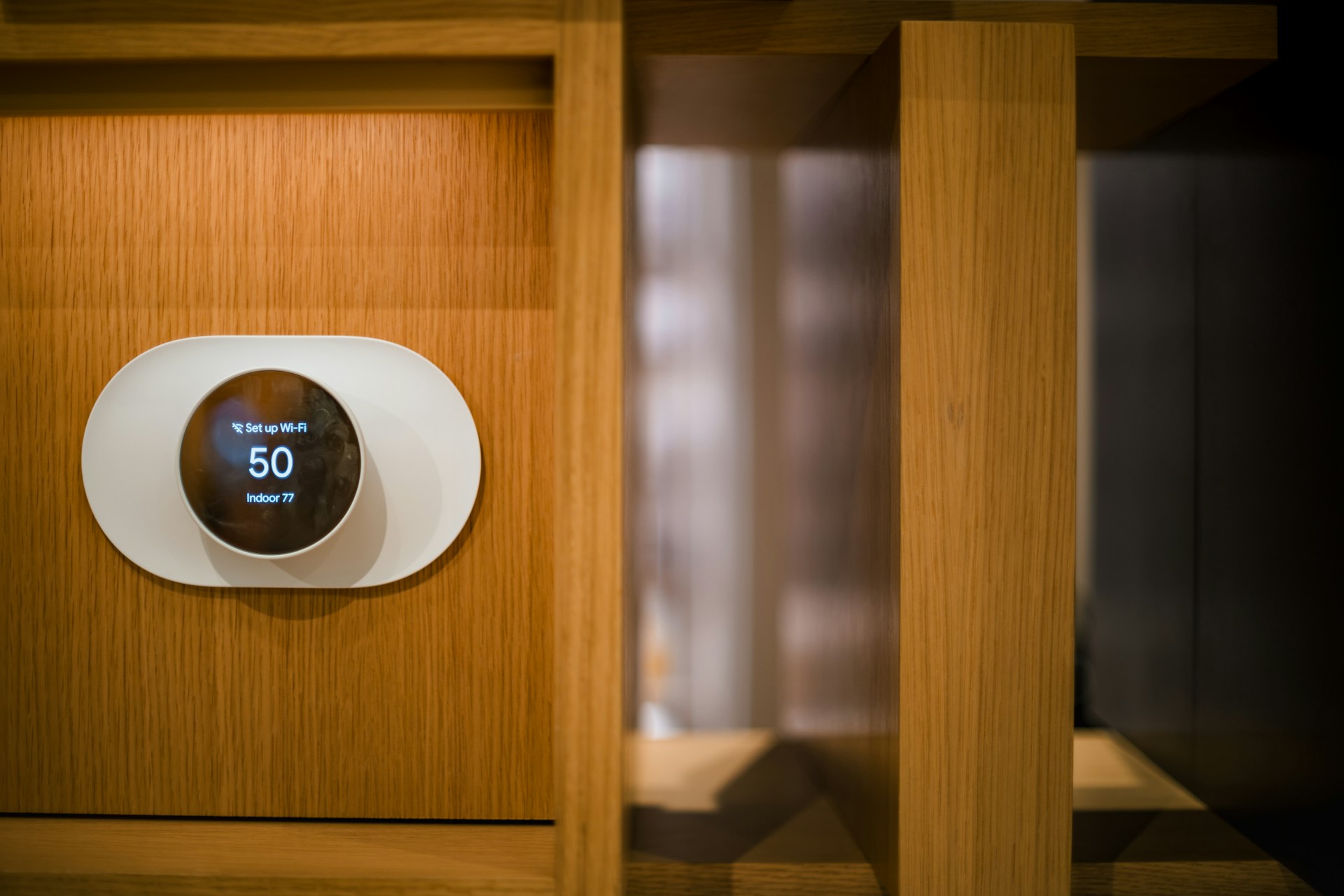 A Google Nest thermostat installed on a wooden wall